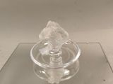 un petit objet en verre posé sur une surface en verre