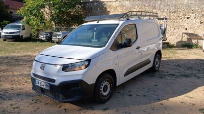 une camionnette blanche garée devant un mur de pierre