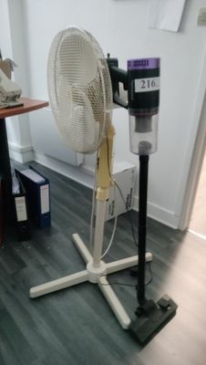 a fan that is sitting on a stand in a room