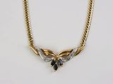 une photo d'un collier en or orné d'une pierre bleue