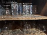 bottles and glasses on a wooden shelf in a room