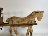 a wooden horse pulling a wagon with a man on it