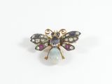 un gros plan d'une broche en forme d'abeille ornée d'une pierre aux couleurs de l'arc-en-ciel