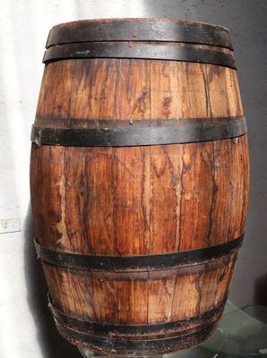 un tonneau en bois posé sur une étagère en verre près d'un mur