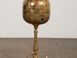 a gold and red vase on a stand on a wooden floor