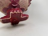 a red and gold vase with a devil figurine sitting on top of it