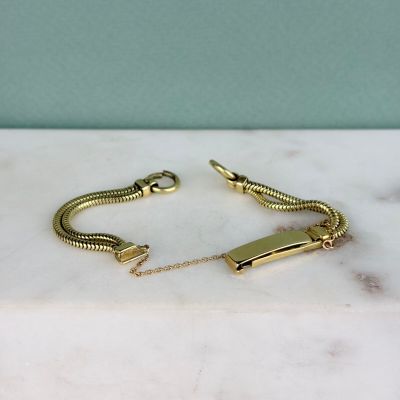 un gros plan d'un bracelet à chaîne en or posé sur une surface en marbre