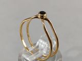 two gold rings with a black stone on top of a clear glass