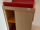a small cabinet with a red seat in the corner of the room