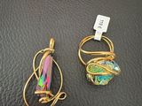 two pieces of jewelry sitting on top of a black leather surface