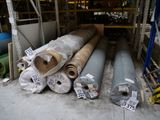 de nombreux rouleaux de tissu posés par terre dans un entrepôt