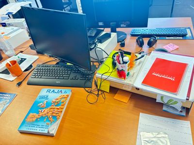 un bureau sur lequel se trouvent un ordinateur, un clavier, des livres et d'autres objets