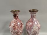 une paire de vases roses et dorés posés sur une surface blanche