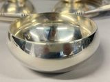 a silver bowl with a spoon in it sitting on a table