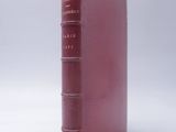 an old red book sitting on top of a white surface