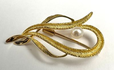 an image of a gold brooch with a pearl in it