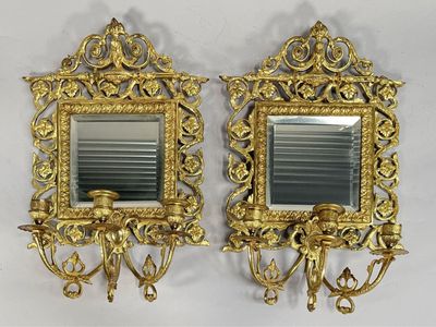 une paire de miroirs dorés accrochés au mur, avec des bougies et un bougeoir