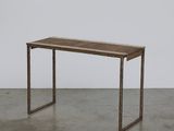 La table est en bois et possède un piètement en métal.