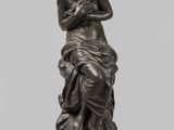 une statue en bronze d'une femme assise sur un rocher