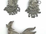 trois bijoux en argent sont exposés sur une surface blanche