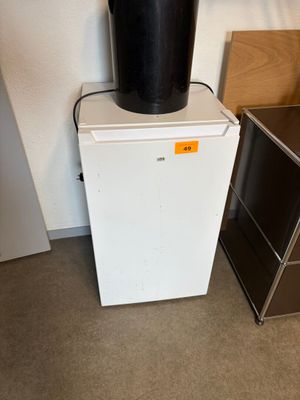 un petit réfrigérateur blanc sur lequel est posé un seau noir