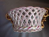 a white and pink basket with gold handles on a table