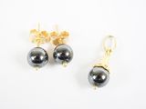 une paire de boucles d'oreilles en perles noires et or sur fond blanc