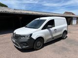 La camionnette blanche est garée devant un garage.