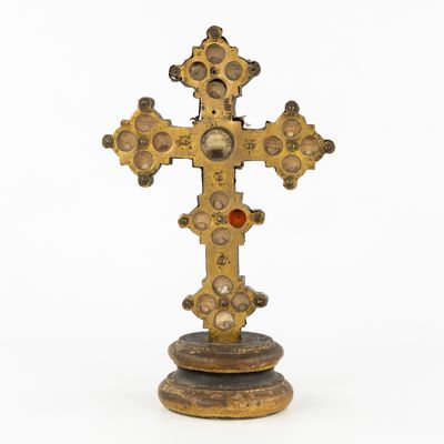 an old gold cross on a wooden base with a red stone in the center