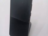 a black cell phone sitting on a stand on a table