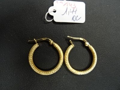 deux paires de boucles d'oreilles créoles en or posées sur une surface noire, accompagnées d'une étiquette de prix