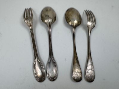 four silver spoons and a fork on a white surface
