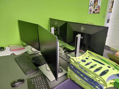 deux écrans et un ordinateur portable posés sur un bureau dans une pièce