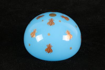 a blue ball with gold bugs on it on a black background