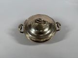 an antique silver plate with a lid and handles on a white surface