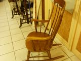 a wooden rocking chair sitting in a room next to a wall