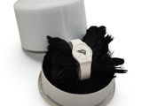 un chapeau blanc orné d'une plume noire sur le dessus