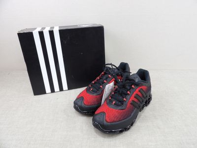 a pair of red and black running shoes next to a black box
