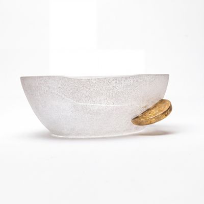 un bol en verre contenant un biscuit, posé sur une surface blanche