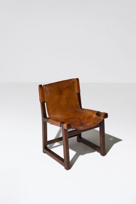 une image représentant un fauteuil en cuir marron posé sur un sol blanc