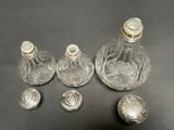 several glass bottles with silver lids on a black surface