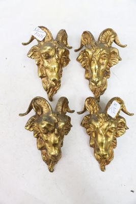 three brass goat head wall sconces on a white surface
