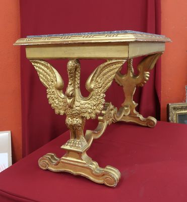 une table dorée sur laquelle se trouve un oiseau, posée sur une table rouge