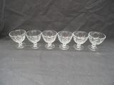 six empty wine glasses lined up in a row on a black background
