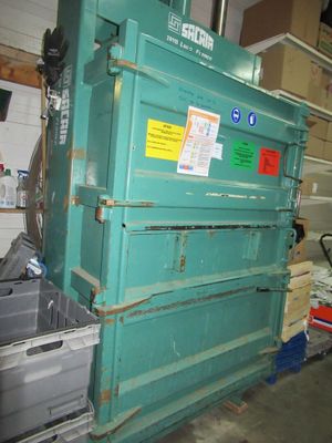 a large green box sitting in a garage next to a pile of boxes