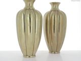 two gold vases sitting side by side on a white surface