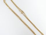 a close up of a gold necklace with a chain on a white surface