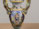 a vase with a painting on it sitting on a table