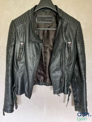 a black leather jacket hanging on a hanger on a wall