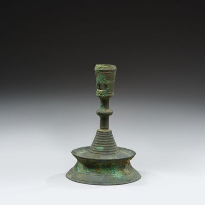 a close up of a metal candle holder on a white surface